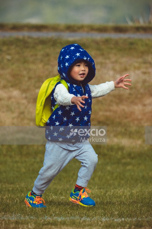 Little girl with yellow backpack and blue jacket with white stars at Little Dribblers