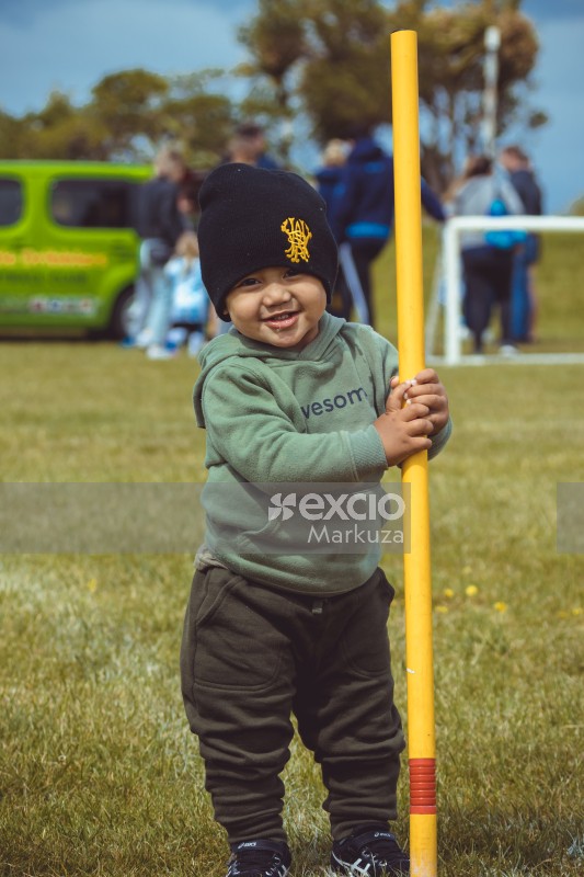 Little boy wearing a cap standing with a yellow pole - Little Dribblers