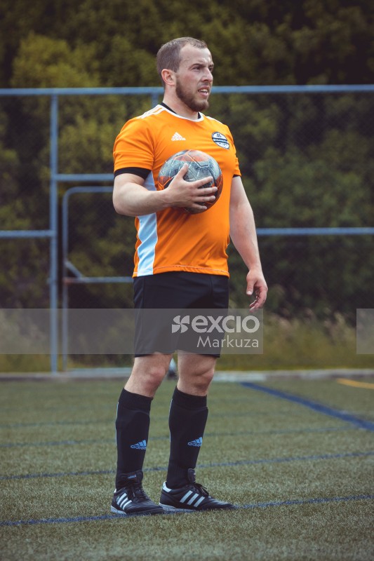 Football player in orange Adidas shirt holding football - Sports Zone sunday league