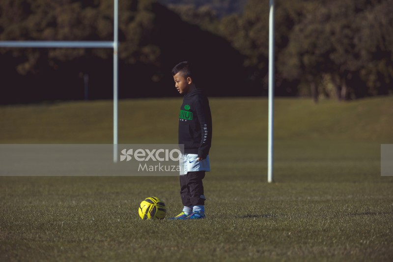 Boy standing with a football at Little Dribblers football match
