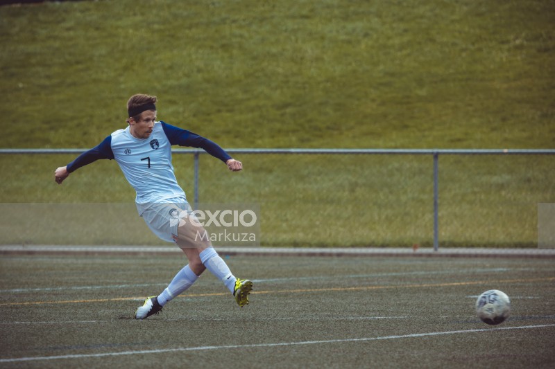 Blue sleeved white shirt player kicks football - Sports Zone sunday league