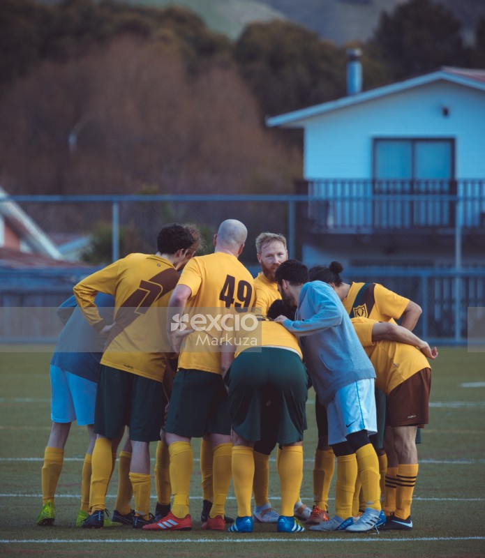 Team members in yellow jerseys huddle at a game - Sports Zone sunday league