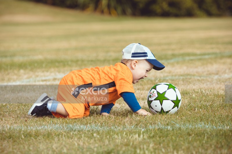 Toddler crawling on grass at Little Dribblers soccer game