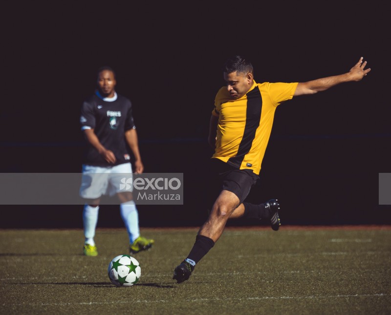 Player at a soccer match in yellow shirt kicking ball - Sports Zone sunday league