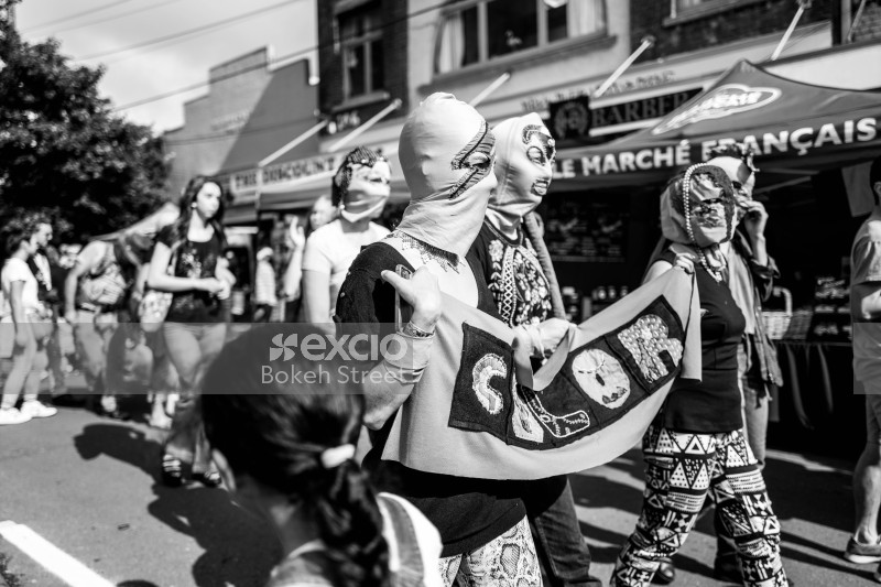 Women in masks hold a banner embroidered letters color at Newtown festival 2021 black and white