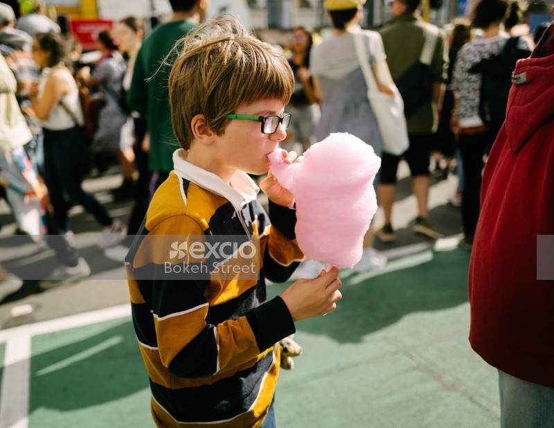 Nerdy kid in black and yellow shirt eating cotton candy at Newtown festival 2021