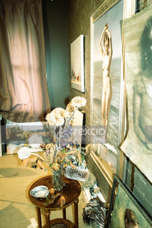 Flowers and jar vase on a table next to artwork