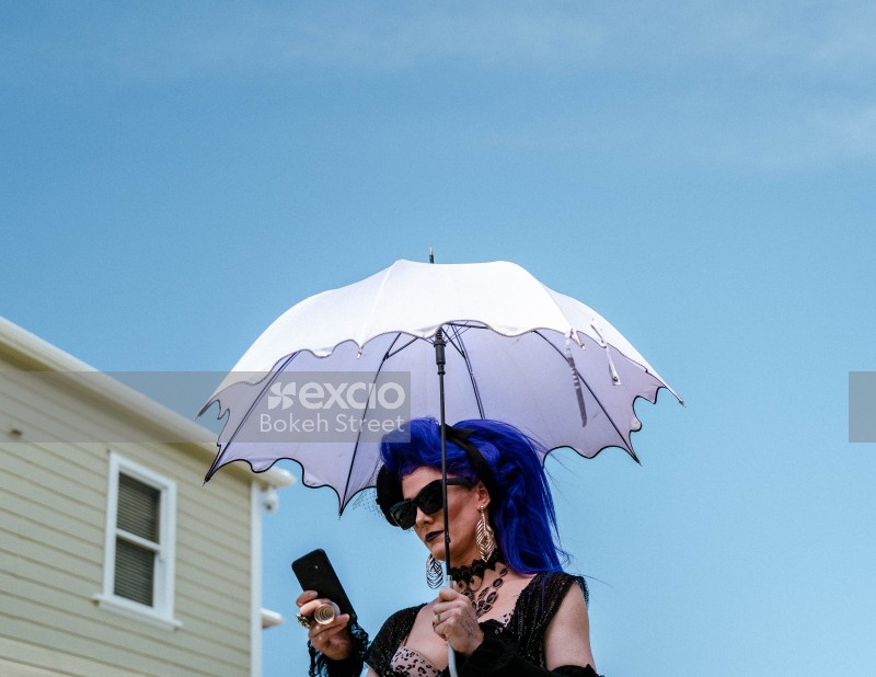 Woman with blue hair holding umbrella