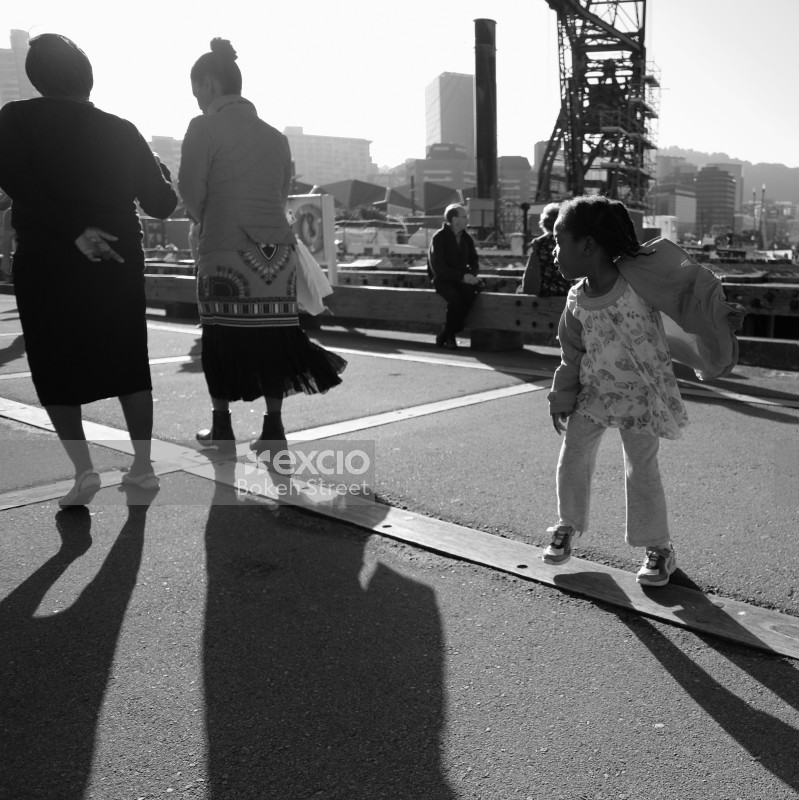 Adults and kid on windy wharf monochrome