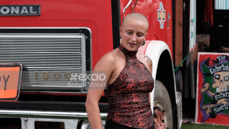 A tattooed bald women in front of a red truck at Waitangi park