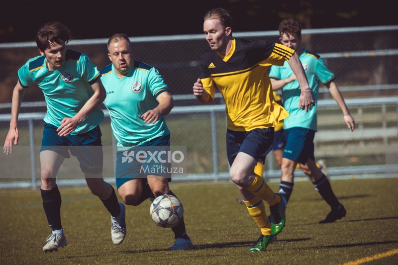 Two players in turquoise shirt chasing after player in yellow shirt - Sports Zone sunday league