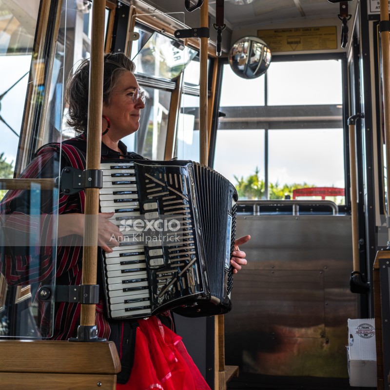 Woman playing piano accordion on cable car