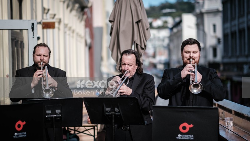 Musicians playing trumpets outdoors in black suits