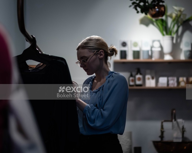Lady wearing blue shirt in a boutique looking at a dress