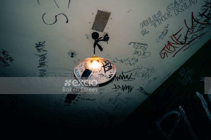 Graffiti on ceiling light shade and dark coloured wall