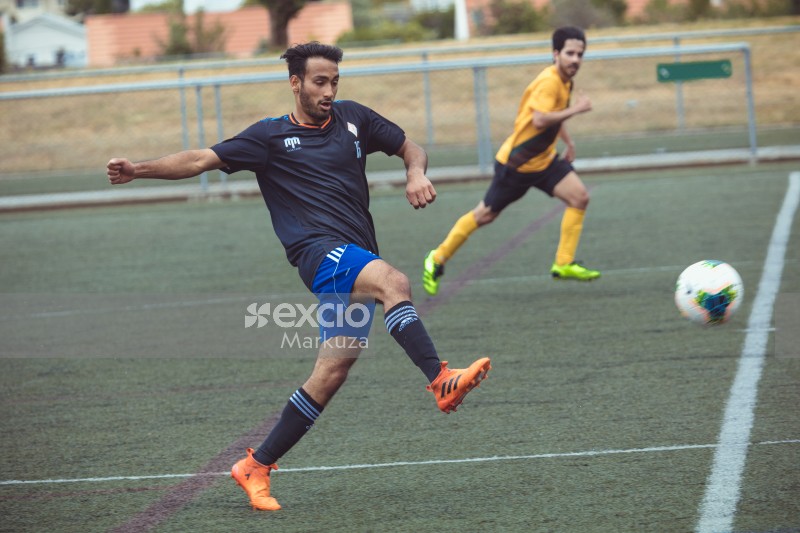 Player in black shirt and orange cleats kicks football - Sports Zone sunday league