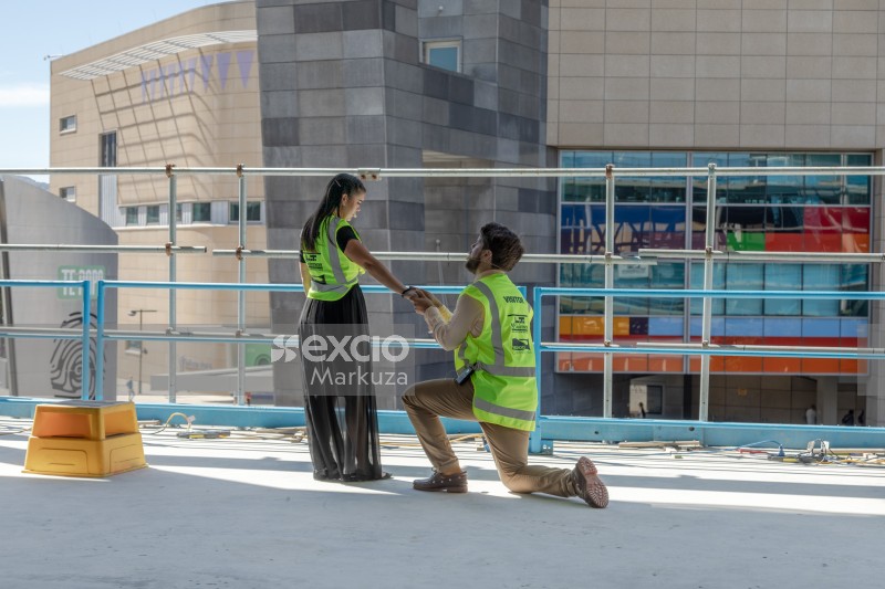 Man kneeling down holding woman's hand high visibility jacket
