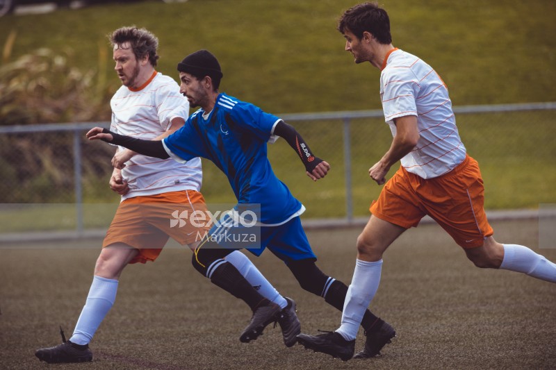 Three football players sprinting towards the ball - Sports Zone sunday league