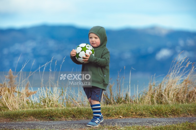 Little girl in green hoodie holding a football - Little Dribblers