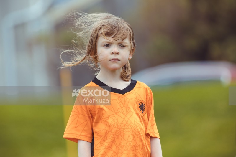 Girl in orange shirt and wind in hair at Little Dribblers football meet