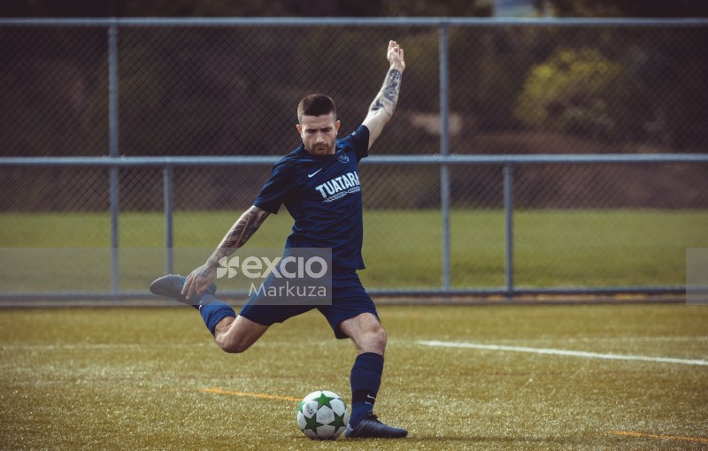Tattooed player in blue Nike kit kicking the ball - Sports Zone sunday league