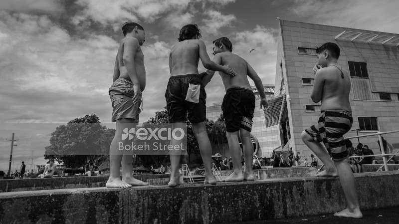Boys in swimming trunks on a stone platform monochrome