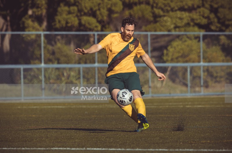 Bearded player kicks football lifting dirt from ground - Sports Zone sunday league