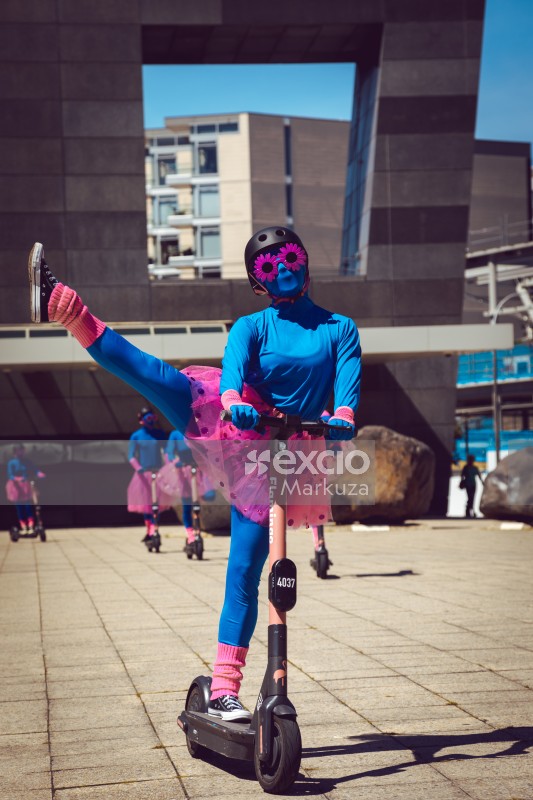 Female artist in a helmet performing flamingo scooter ballet