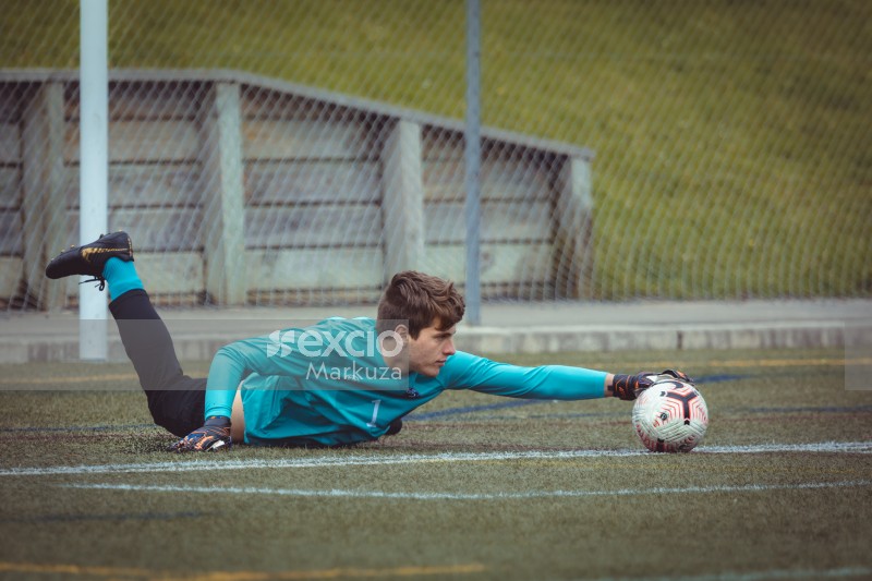 Goalkeeper lying on the ground extending hand to stop football - Sports Zone sunday league