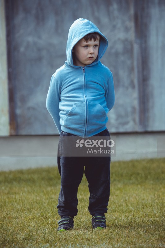 Boy wearing a light blue hoody standing on the grass - Little Dribblers