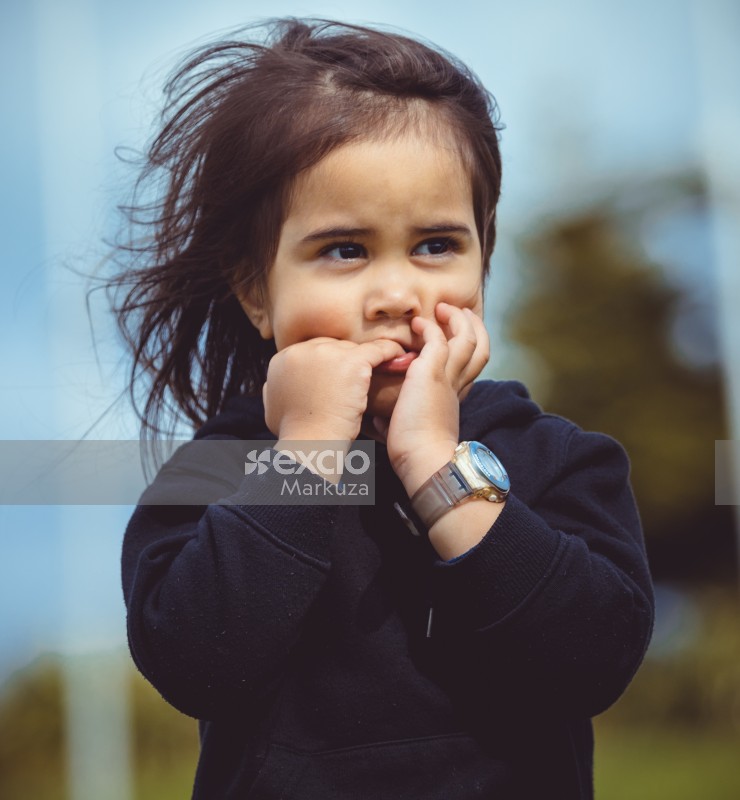 Little girl in a black hoodie biting on pinkie finger - Little Dribblers