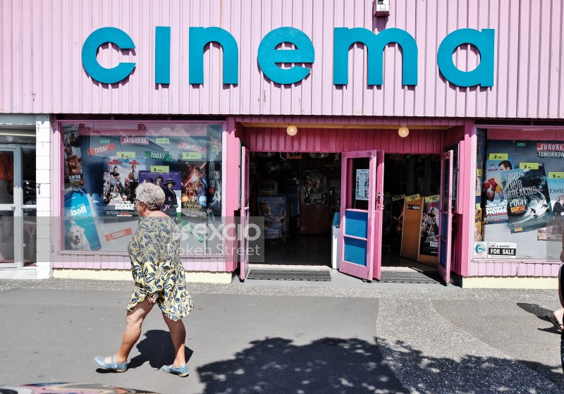 Old woman walking in front of a cinema