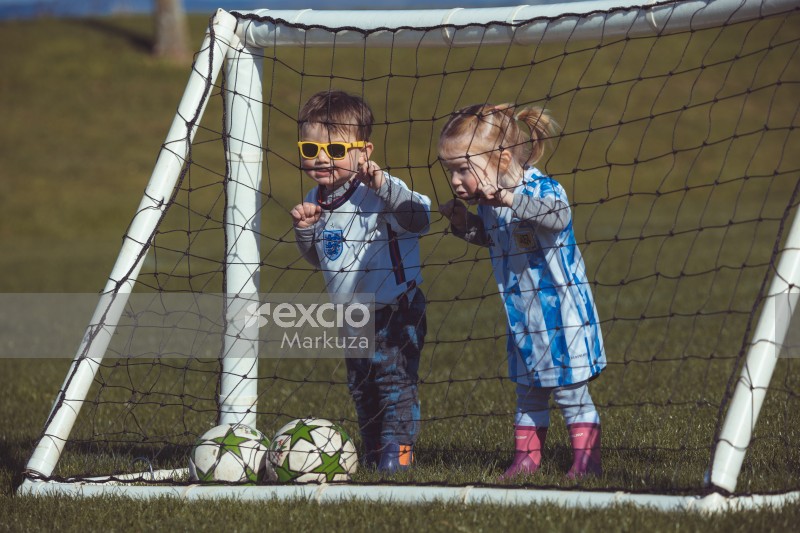 Boy and girl grabbing net of a football goal post