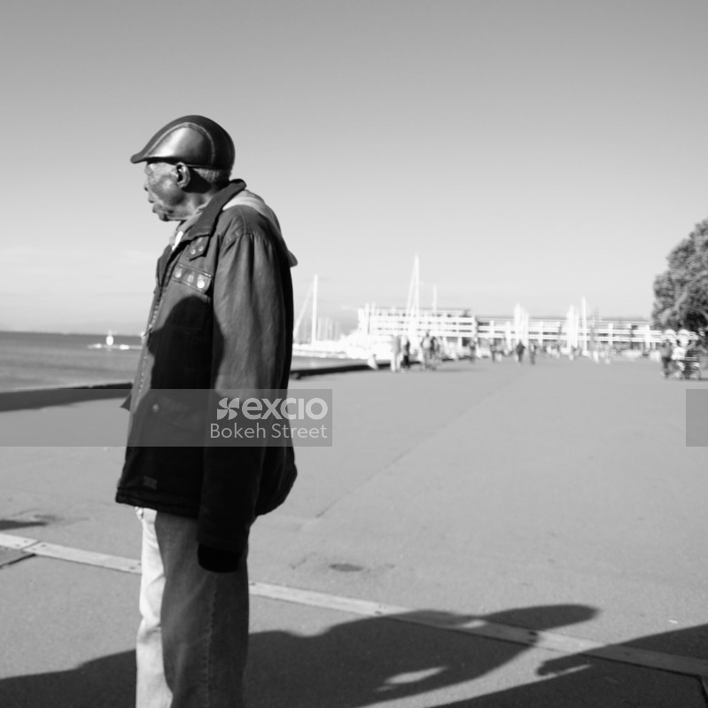 Old man in a jacket looking at the sea monochrome
