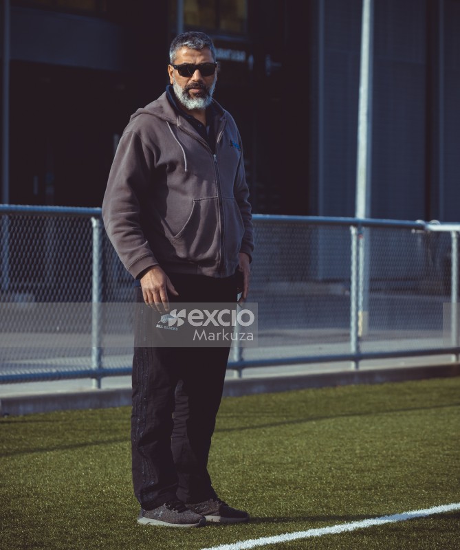 Guy with a beard and sunglasses spectate from sidelines - Sports Zone sunday league