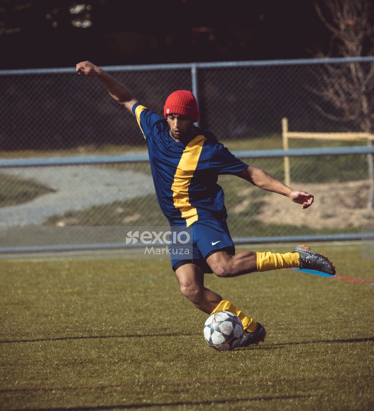 Football player with red beanie cap kicking ball - Sports Zone sunday league