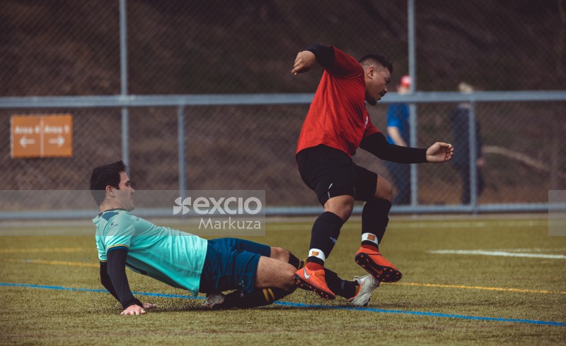 Player  in turquoise shirt slide tackling opponent from behind - Sports Zone sunday league