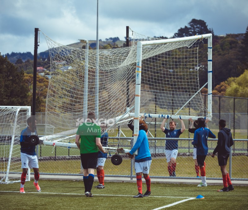 Football players carrying over a portable goal post onto another field - Sports Zone sunday league