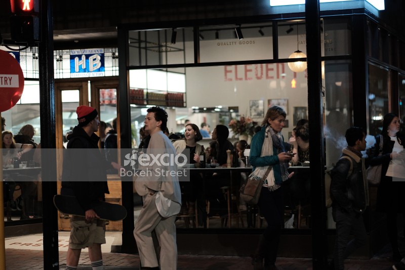 People in the street and inside restaurant at night