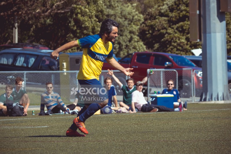 Guy in blue and yellow football kit running at Sports Zone sunday league
