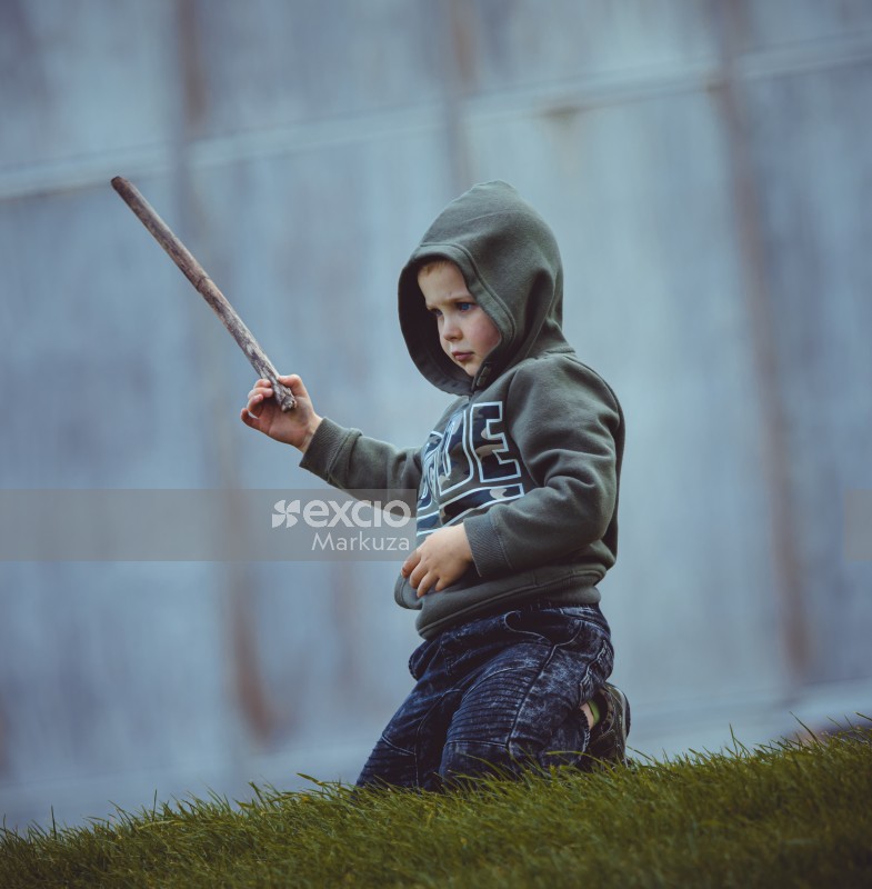 Blue eyed boy wearing hoodie with a wooden stick in his hand - Little Dribblers