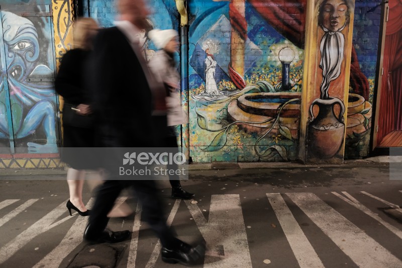 People walking past a wall with artwork