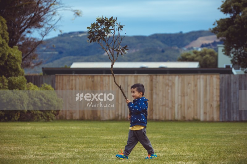 Little boy walking with a tree branch - Little Dribblers