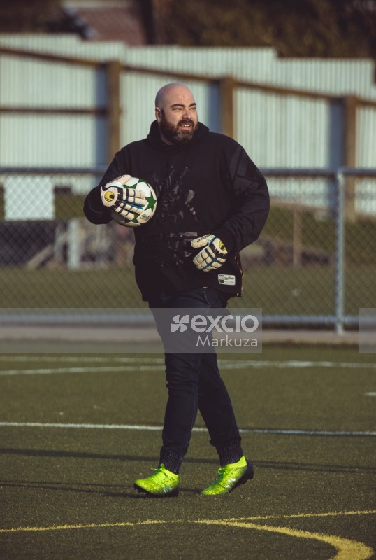 Goalkeeper with lime cleats and black hoodie holding football - Sports Zone sunday league