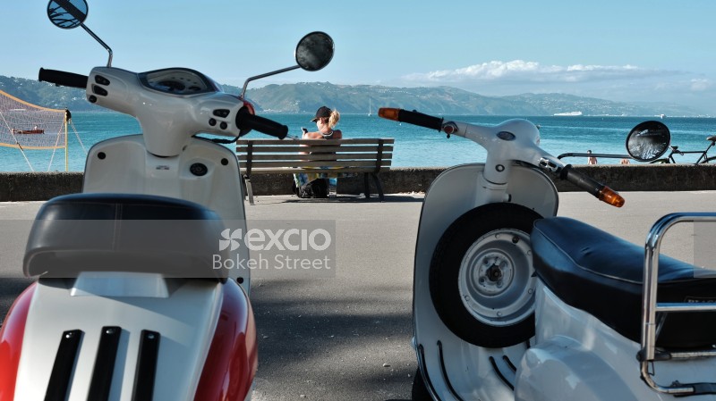 Old scooters and coastal view from a bench