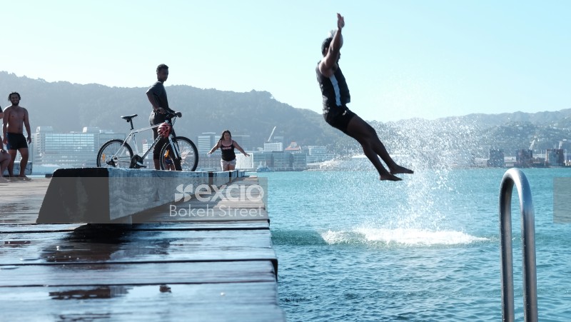 Guy dive bombing from pier into water