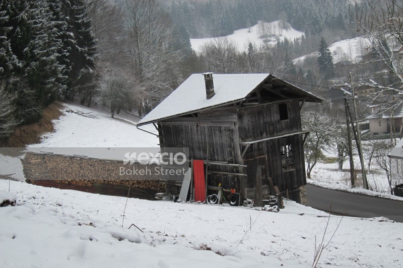 Snow covered wood shack and fire wood logs at the Swiss Alps
