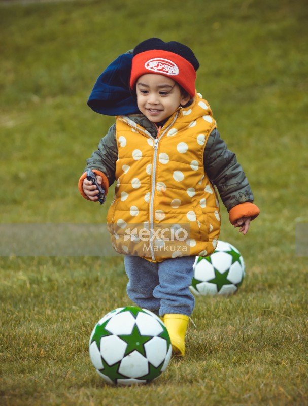 Little girl in yellow polka dot jacket playing football - Little Dribblers