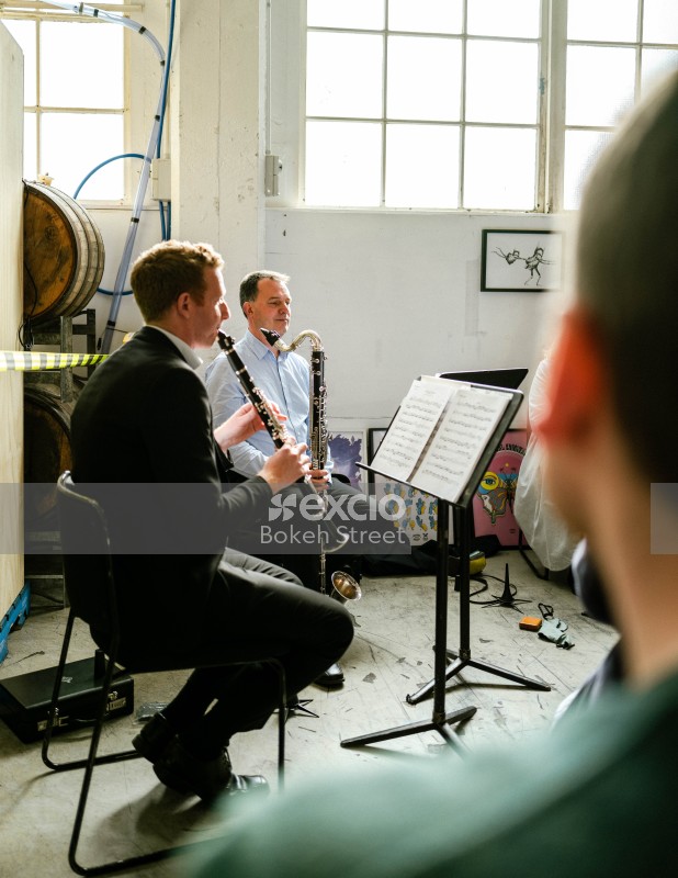 Musicians playing clarinet and bassoon next to paintings in a brewery
