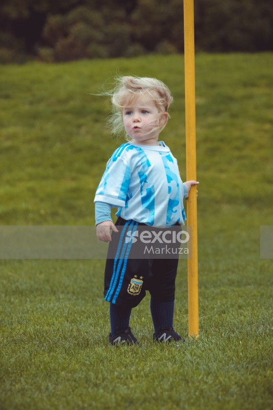 Blonde girl in striped shirt holding a yellow pole